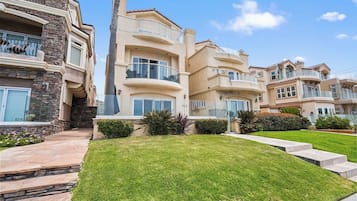 A multi-story residential building with balconies, a stone facade, and a well-maintained lawn.