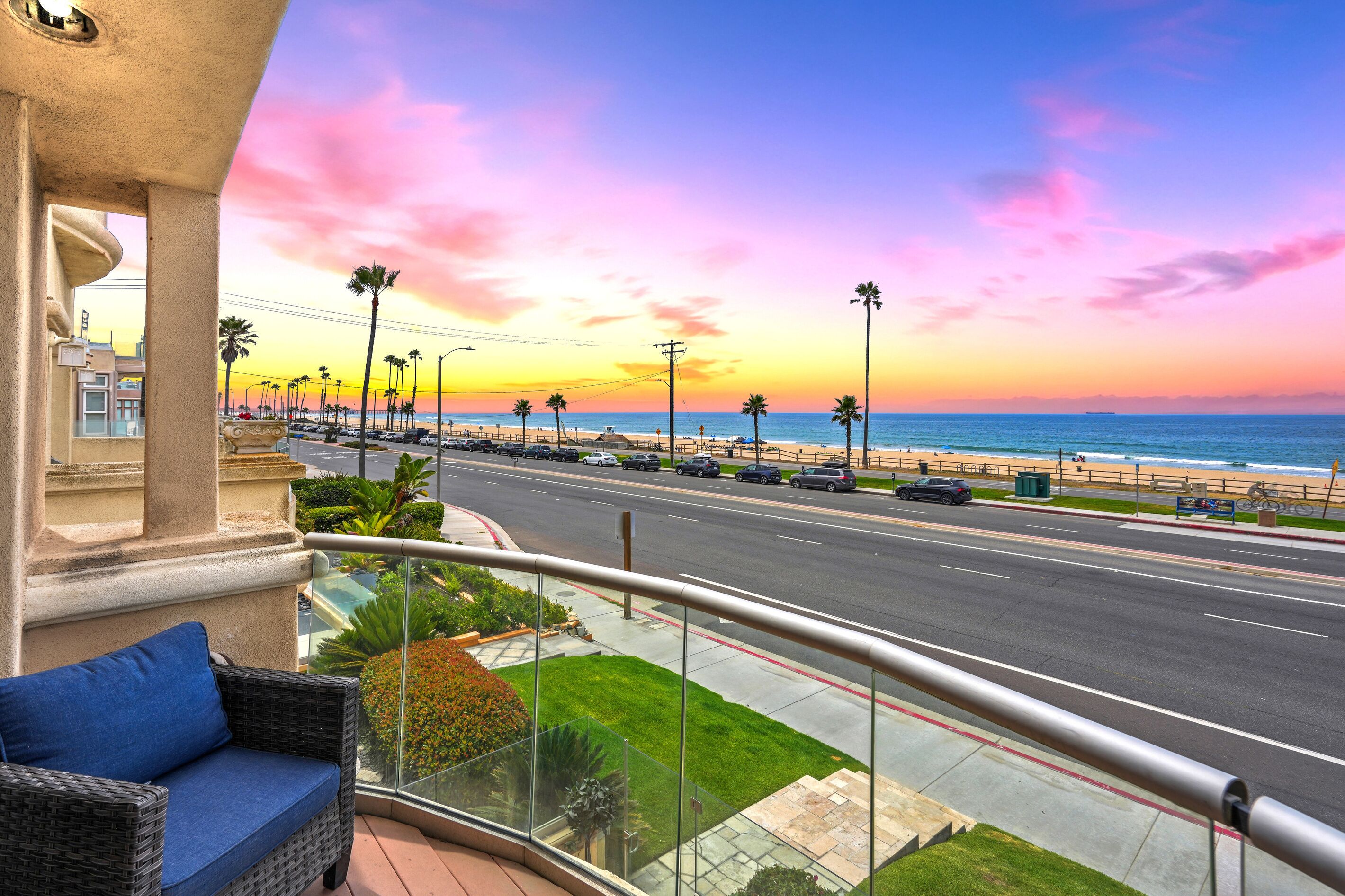 Un balcon donnant sur une plage et une route au coucher du soleil.