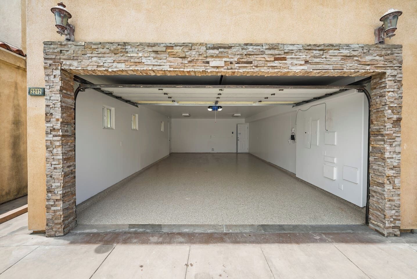 A hallway with a stone facade, a door on the right, and a number '2212' sign on the left.