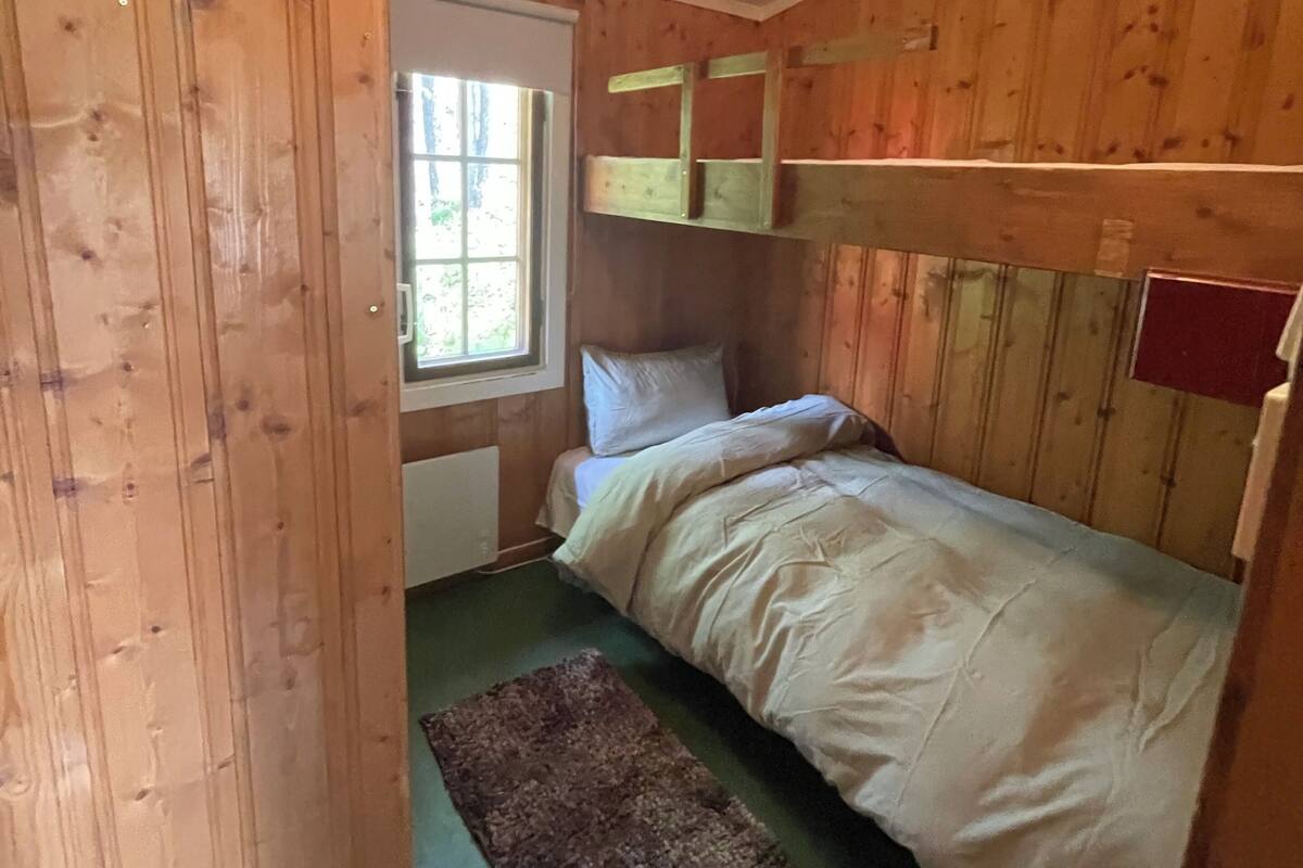 Une pièce de style cabane en bois, avec un lit, une fenêtre et un radiateur.