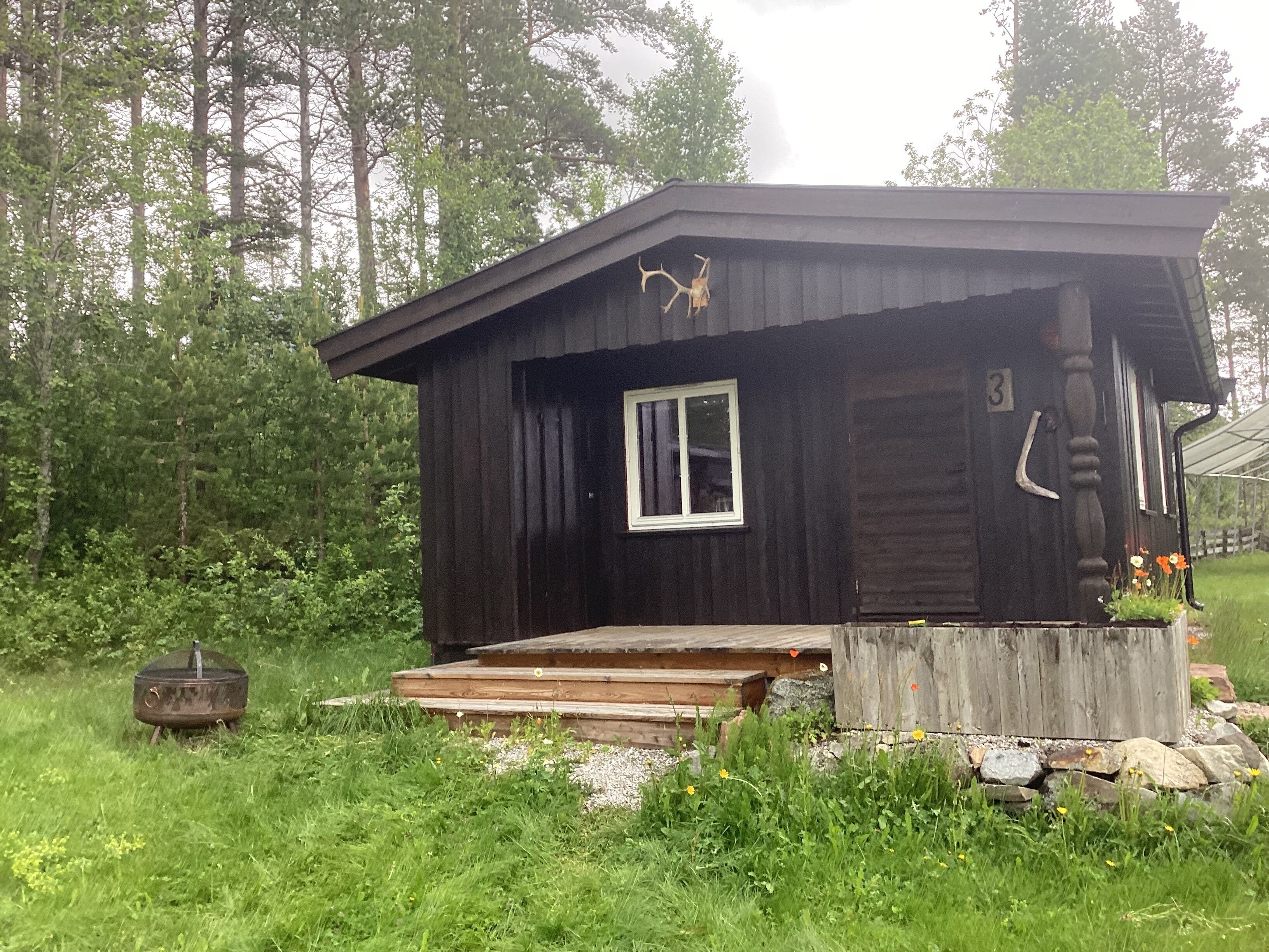 Eine rustikale Holzhütte mit einer kleinen Fenster und einer Veranda.