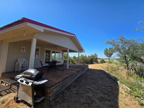 A covered outdoor area with a barbecue grill, a table, and chairs.