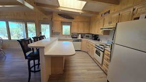 Une cuisine moderne avec des meubles en bois, un îlot central et un grand réfrigérateur.