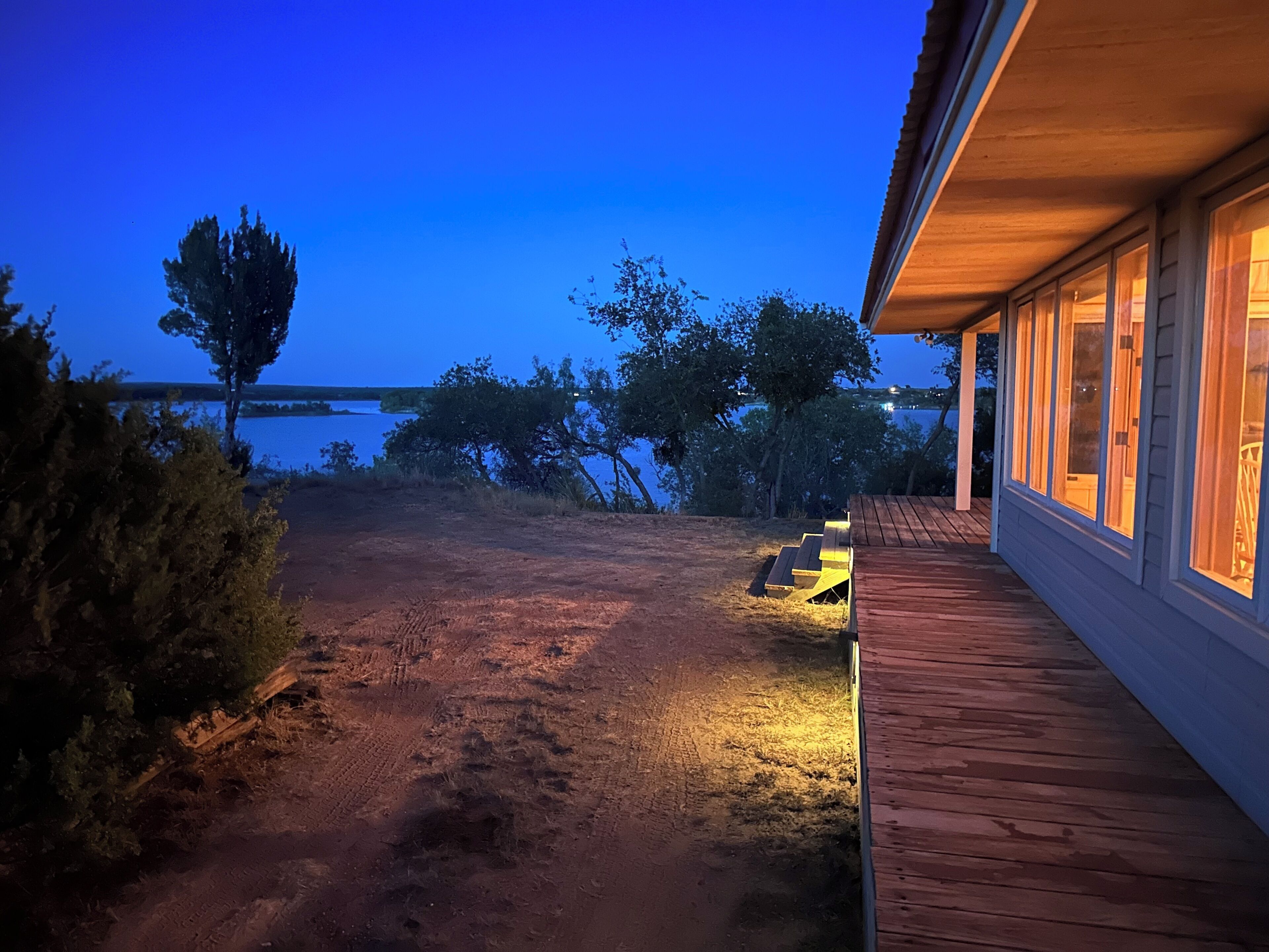 A wooden deck with a view of a lake at dusk.
