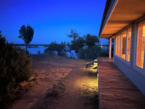 A wooden deck with a view of a lake at dusk.