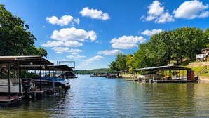 Un lac paisible où sont amarrés des bateaux, avec des espaces de repos abrités et une végétation luxuriante.