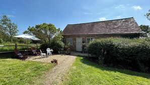 Ein Haus mit Backsteinfassade, einer Holzdielen-Terrasse und einem Gartenbereich mit Gartenmöbeln.