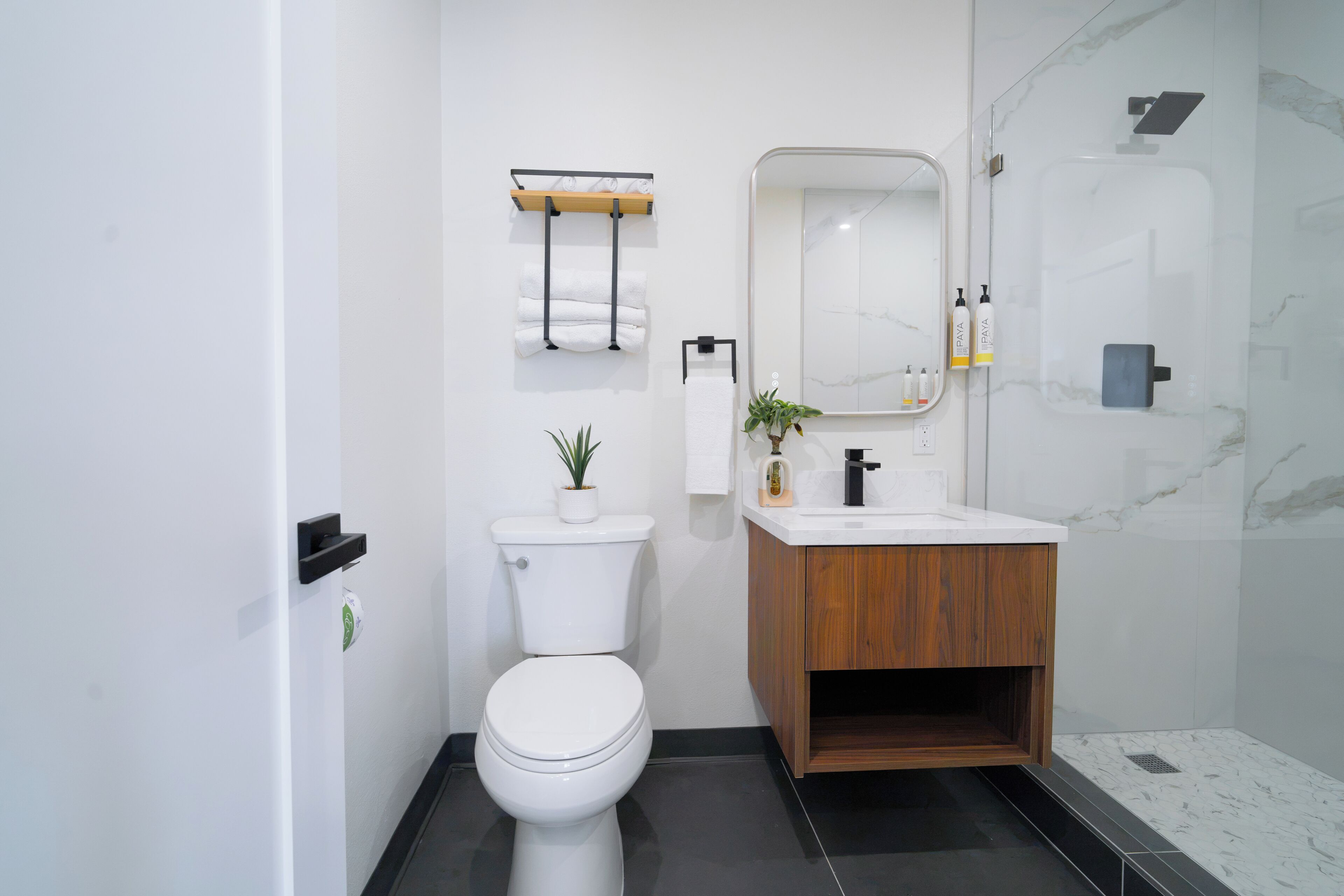 A modern bathroom with a toilet, sink, mirror, and shower.