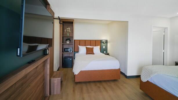 A hotel room with a bed, a TV, a microwave, and a small cabinet. - Nox Hotel - Studio City (Studio City)