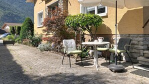 Un patio con mobiliario exterior, una mesa y un paraguas blanco.