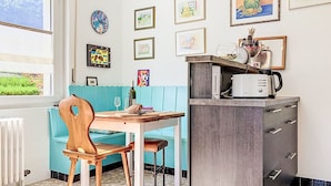 Una cocina con una mesa de comedor, sillas, un microondas y un armario.