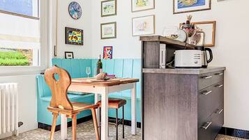 Une cuisine équipée d’une table à manger, de chaises, d’un four à micro-ondes et d’un meuble de rangement.