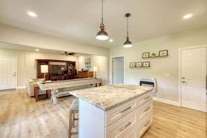 A kitchen with a central island, wooden cabinets, and pendant lighting.