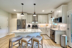 A modern kitchen with a central island, stainless steel appliances, and pendant lighting. - Beautiful lake side retreat in the Blue Ridge Mountains of north Georgia. (Blairsville)