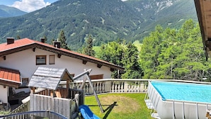 Une maison avec une piscine, un toboggan et une vue sur les montagnes.