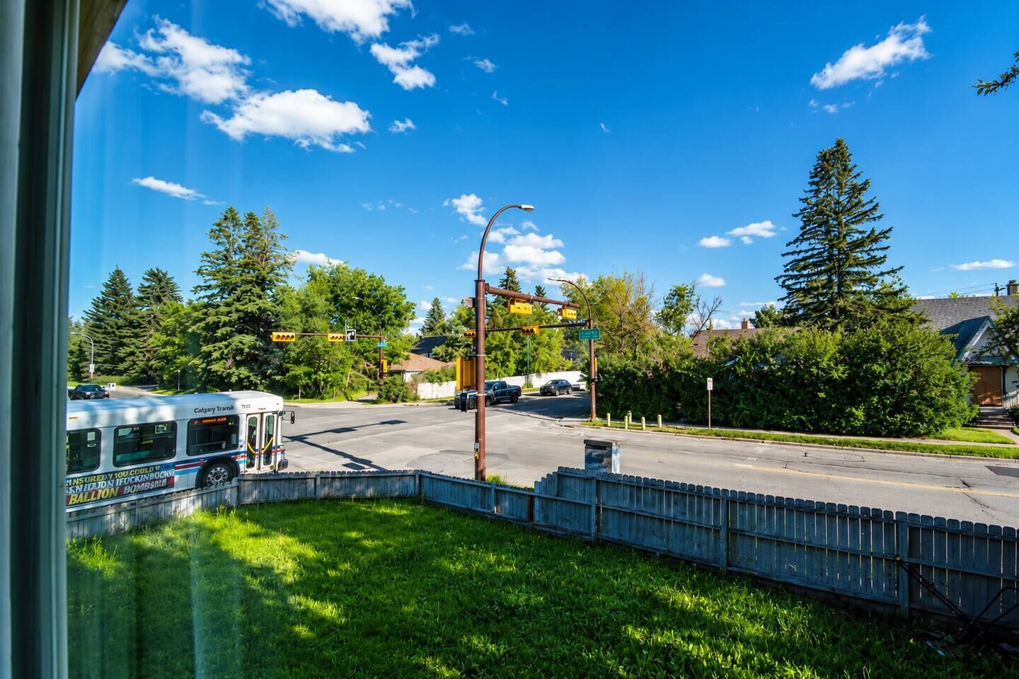 A bus stop with a bus, a street intersection, and trees.