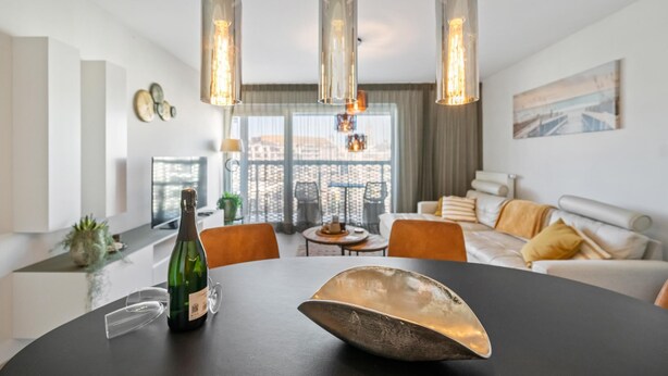 Una sala de estar moderna con una mesa de comedor, un sofá y lámparas colgantes.