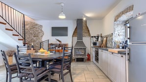 Uma cozinha moderna com parede de pedra, forno embutido e espaço de refeições com mesa e cadeiras.