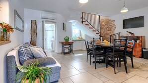 Uma sala de estar moderna com sofá, mesa de jantar, cadeiras e escada.