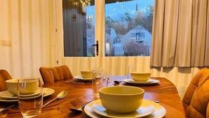 A dining table set with bowls, glasses, and cutlery, with a view of trees and buildings through the window. - 4-guest Elegant Holiday Base in Hotton (Hotton)