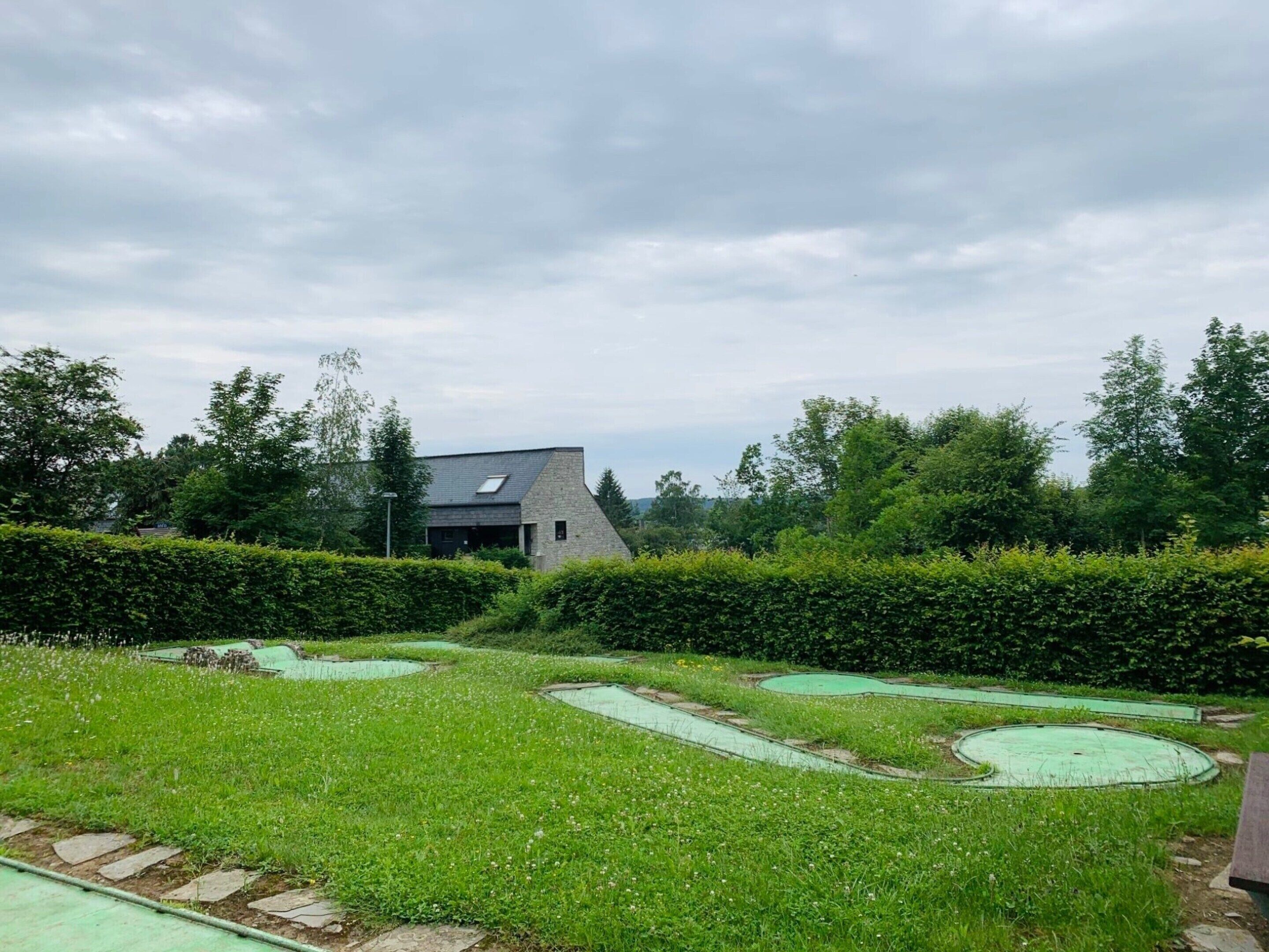 Ein modernes Haus mit Naturstein-Fassade, umgeben von einem gepflegten Rasen und einer Hecke.
