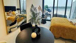 Ein modernes Hotelzimmer mit einem großen Bett, einem runden Tisch, einem Spiegel und Blick auf die Stadt.