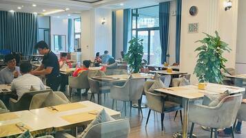 A spacious dining area with tables and chairs, a projector, and large windows.