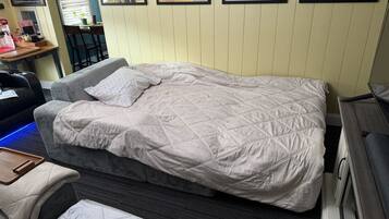 Un letto singolo con copriletto trapuntato, un comodino, una sedia e un tavolino con vassoio.