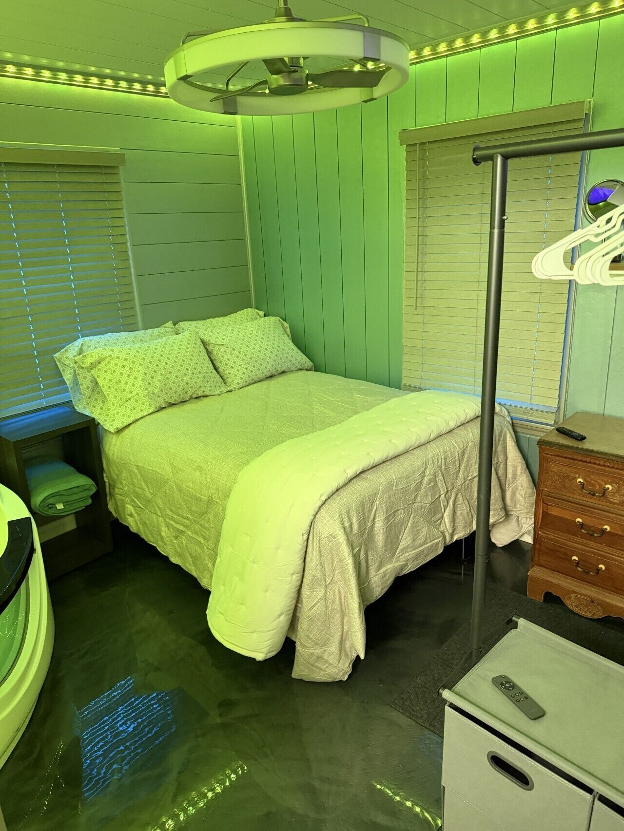 Ein Zimmer mit Bett, Kommode, Spiegel und Deckenventilator.