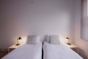 A twin room with two single beds, each with a bedside table and a lamp.