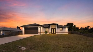A modern single-story house with a garage, a well-maintained lawn, and a clear sky at dusk.