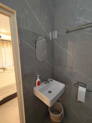 Ein Badezimmer mit weißem Waschbecken, einem Spiegel, einem Handtuchhalter und einer Toilette.