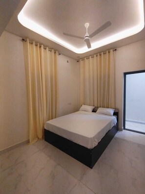 Ein Schlafzimmer mit Bett, Vorhängen, Deckenventilator und Blick durch ein Fenster.