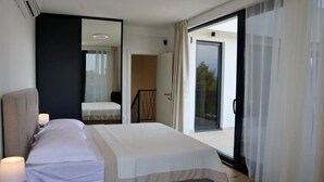 A modern bedroom with a bed, bedside table, and a view of the outside through a sliding glass door. - Sunset Villa Aves With Pool, Gym and Sauna - Four Bedroom Villa (Rogac)
