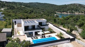 A modern two-story house with a swimming pool, surrounded by greenery and a view of the sea. - Sunset Villa Aves With Pool, Gym and Sauna - Four Bedroom Villa (Rogac)