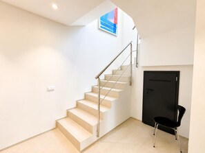 A modern interior with a staircase, a black door, and a chair. - Villa Belleza - Santa Cristina d'Aro, Catalonia (Santa Cristina d'Aro)