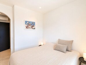 A bedroom with a bed, a painting, a nightstand, and a door. - Villa Belleza - Santa Cristina d'Aro, Catalonia (Santa Cristina d'Aro)