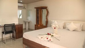 Una habitación de hotel con una cama, un escritorio, una silla, un espejo y un lavamanos.