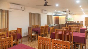 Un comedor con mesas y sillas de madera, unidades de aire acondicionado y ventiladores de techo.