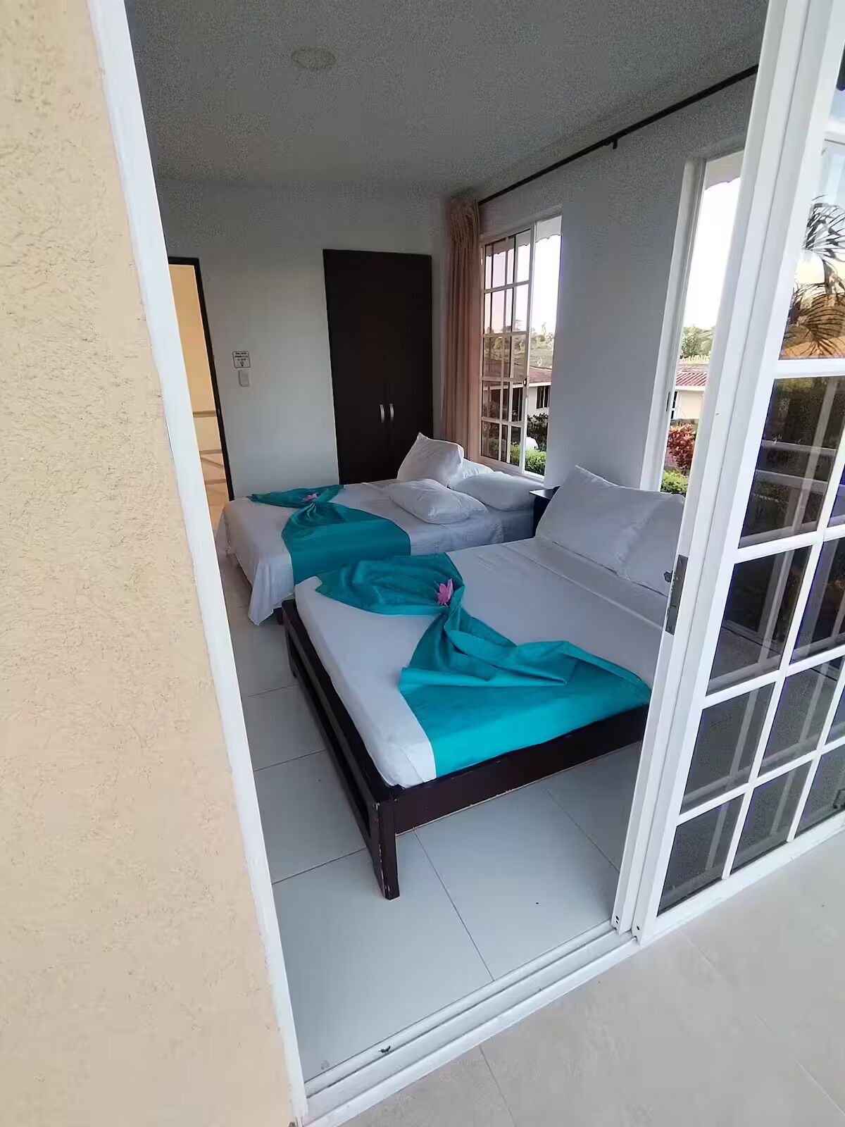 Una habitación con dos camas, un ventanal corredero y vistas al exterior.