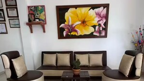 A living room with a sofa, two armchairs, a coffee table, and a large floral painting on the wall. - El Amanecer Farm Hotel (Quimbaya)