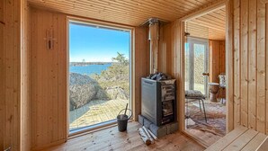 A wooden cabin with a fireplace, a view of the water, and a stone table. - Lovely home in Saltsjöbaden with sauna (Saltsjöbaden)