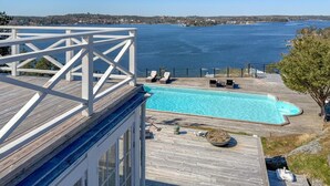 A wooden deck with a swimming pool, lounge chairs, and a view of the sea. - Lovely home in Saltsjöbaden with sauna (Saltsjöbaden)