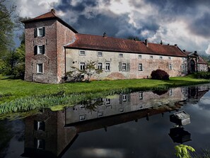Historiallinen rakennus, jonka edessä on suuri, heijastava lampi. Rakennuksessa on tiiliverhous ja useita ikkunoita.