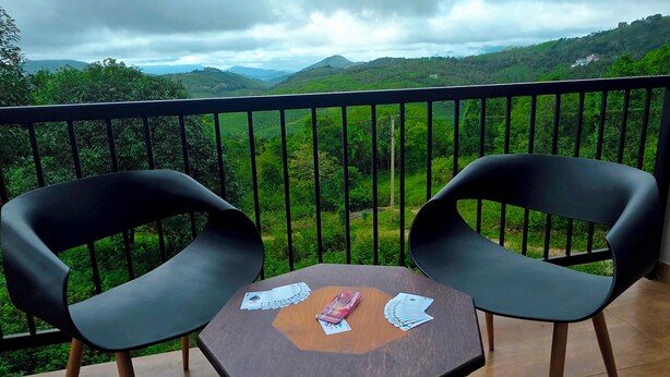 Ein Balkon mit zwei Stühlen und einem kleinen Tisch, der einen üppigen, grünen Ausblick bietet.