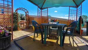 An outdoor patio with a table and chairs, a wooden fence, and a pergola structure. - The Mini Place, Buffalo (Buffalo)