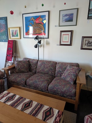 Ein Wohnzimmer mit einem gemusterten Sofa, einem Holztisch und einem Teppich.