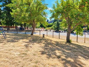 Un parc avec des arbres, une aire de jeux et un espace clôturé.