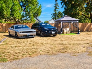 Deux voitures sont garées dans une cour, avec une tente et une clôture en bois en arrière-plan.