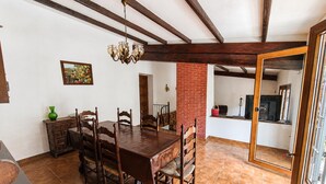 A dining area with a wooden table and chairs, a chandelier, a painting, and a brick wall.